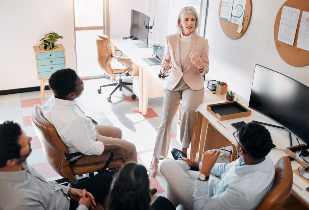 High angle shot of a mature businesswoman sitting and training her team in the office.